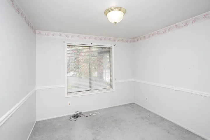 Room featuring a single window with blinds, wall molding, and a decorative border