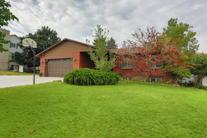 Brick exterior with a brown garage door, front-facing gabled roof, and mature landscaping