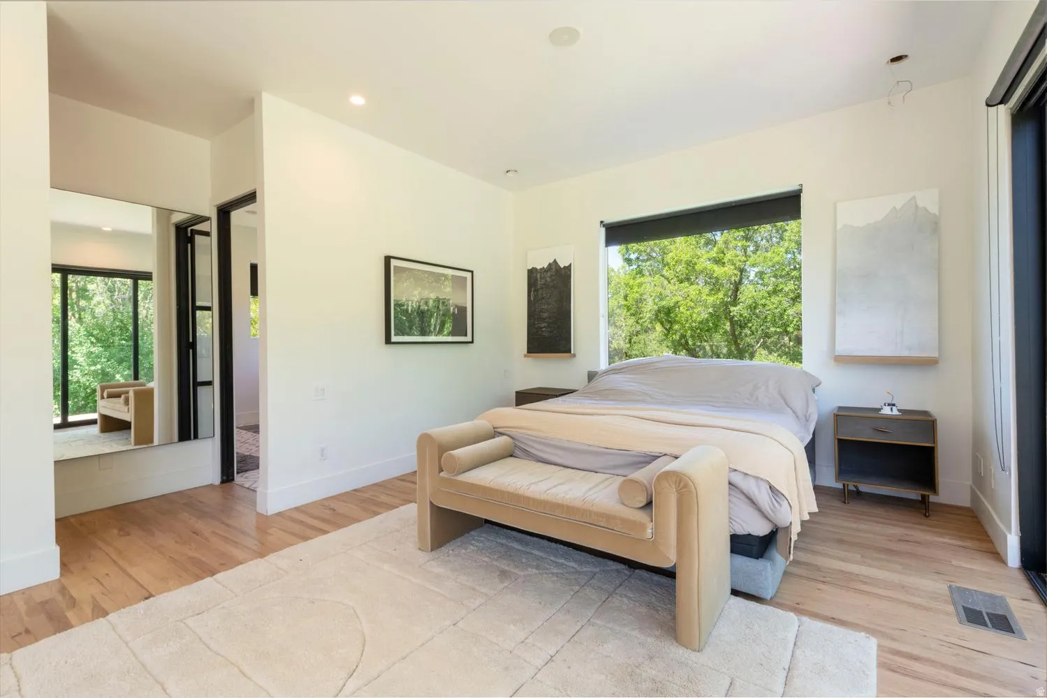 Primary suite featuring wood-finish flooring, a full-height mirror, recessed lighting, and a large picture window