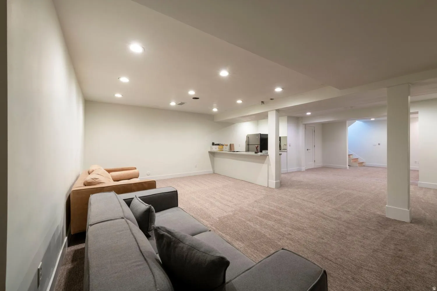 Spacious lower level featuring recessed lighting, plush carpeting, a built-in wet bar with cabinetry, and a refrigerator