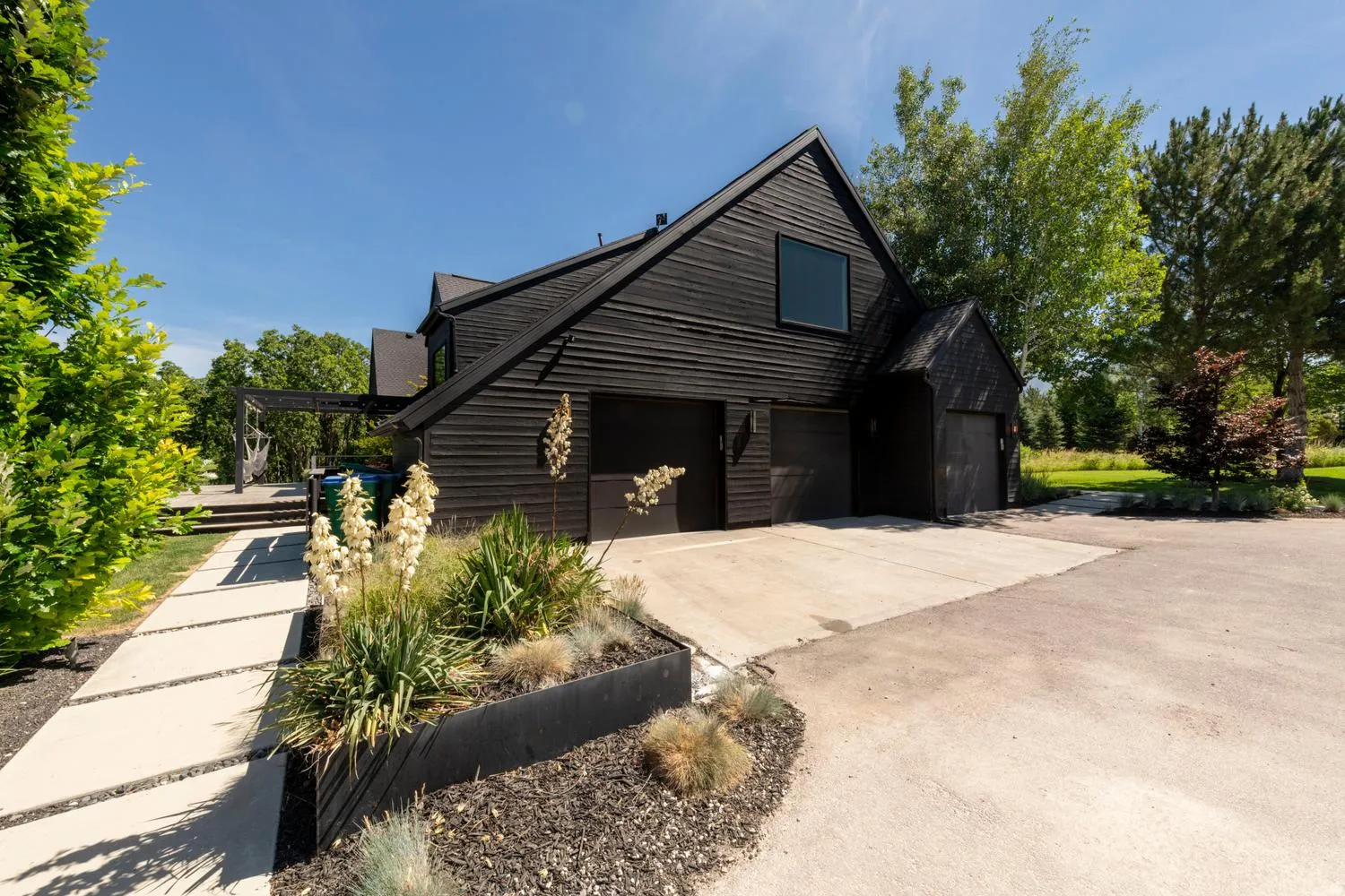 Contemporary dark-clad exterior featuring multiple garage bays, a prominent pitched roofline, and a modern window