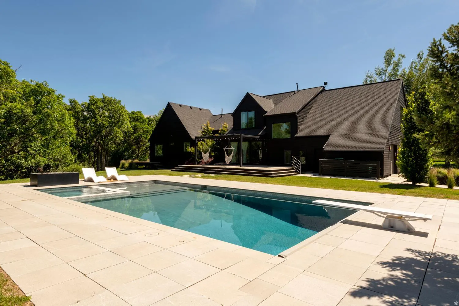 Expansive outdoor living area featuring a rectangular pool with an integrated spa