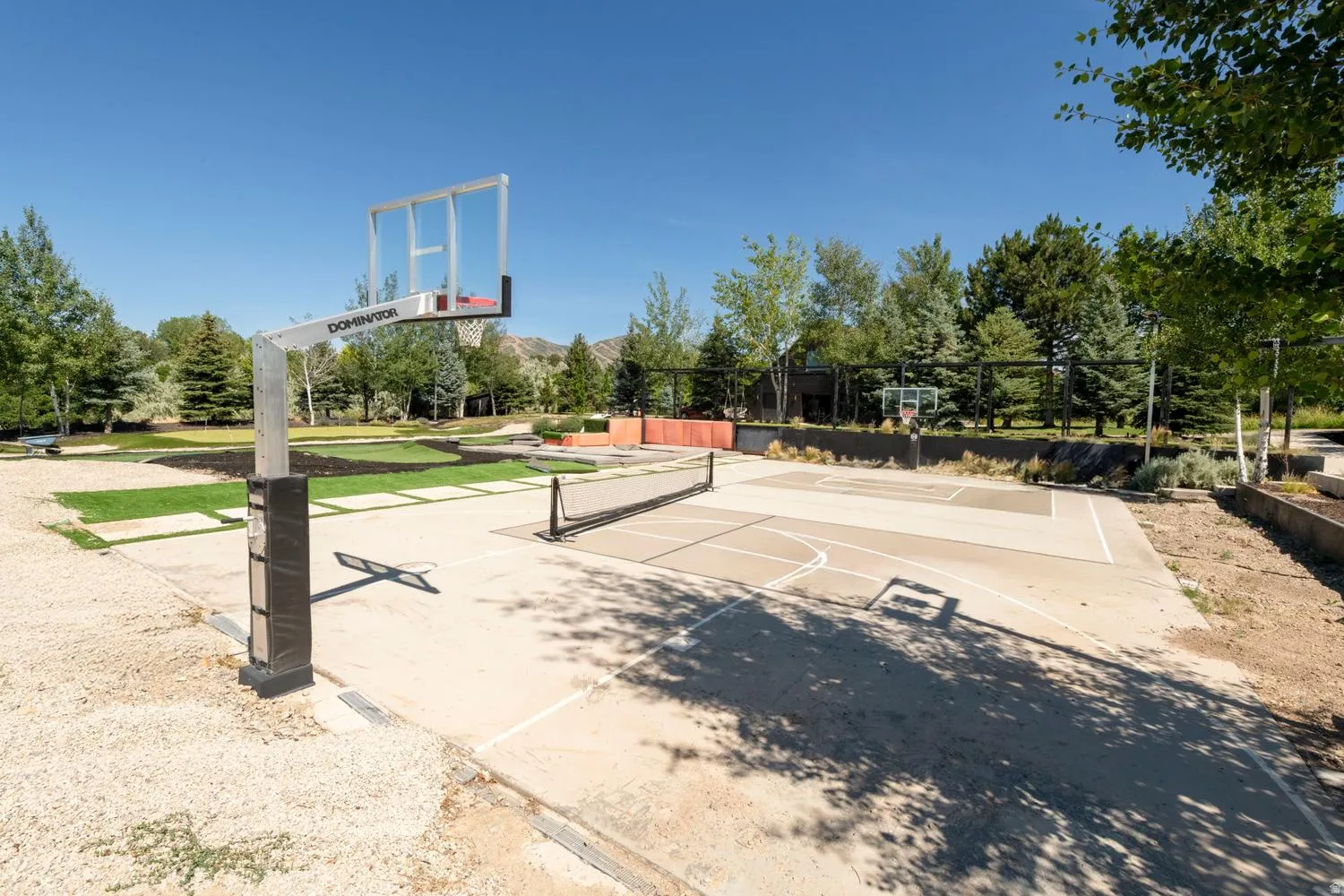Outdoor sports court featuring basketball hoops and a pickleball net for additional recreation