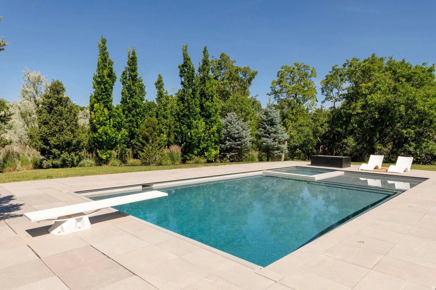 In-ground swimming pool with diving board, integrated spa, and surrounding pool deck