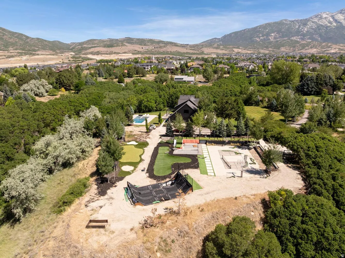 Extensive outdoor entertainment area featuring a putting green, swimming pool, and dedicated court space