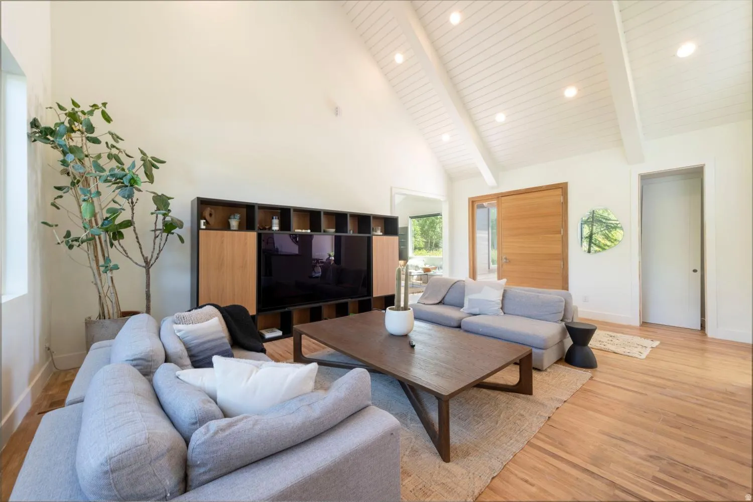 Living area featuring vaulted ceilings with exposed white beams and recessed lighting