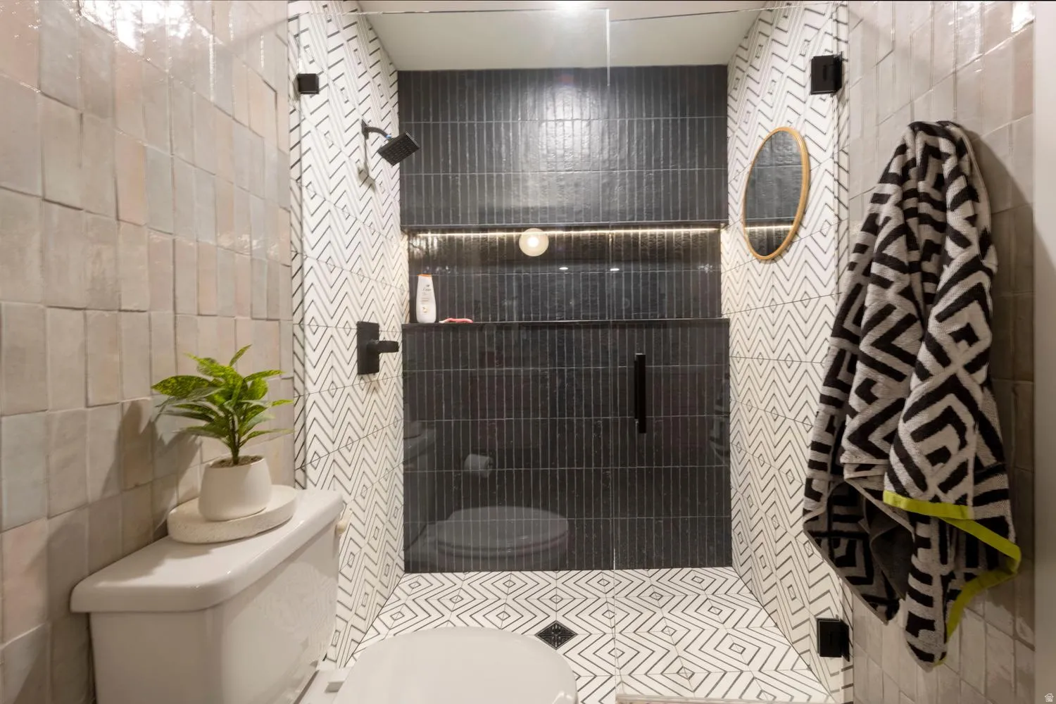 Contemporary shower enclosure featuring black vertical tile, integrated lighting, and a recessed niche