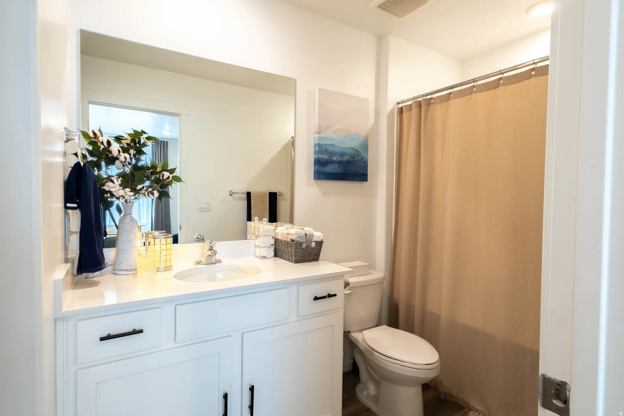 White vanity with a single basin sink, light-toned countertop, and matte black hardware