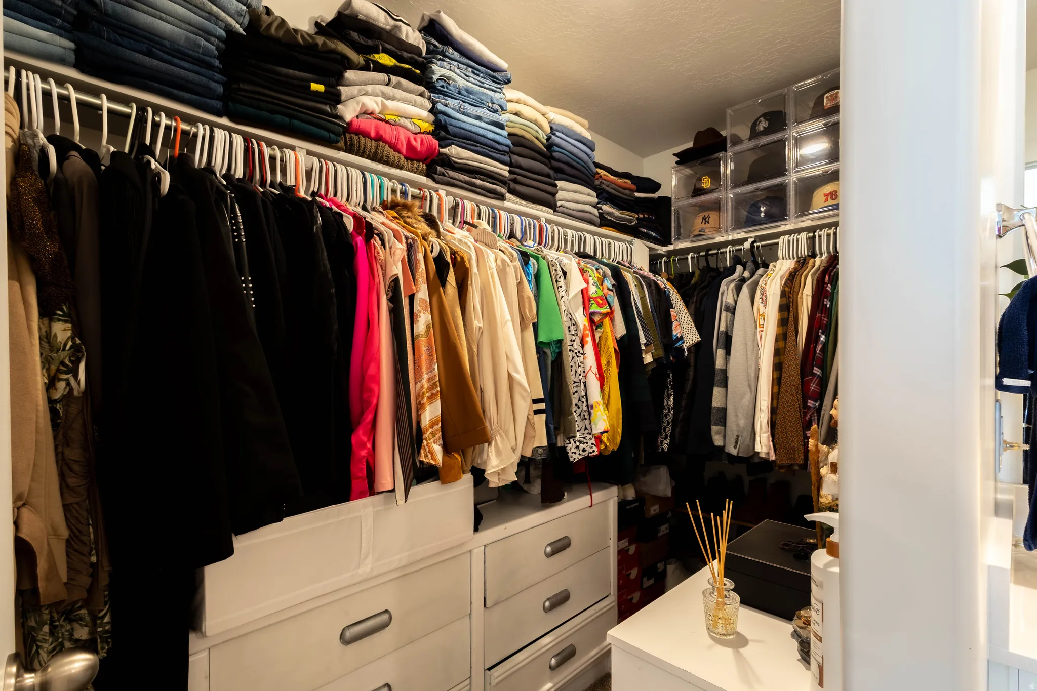 Custom closet system featuring multiple hanging rods, integrated shelving, and white drawer cabinetry with contemporary hardware