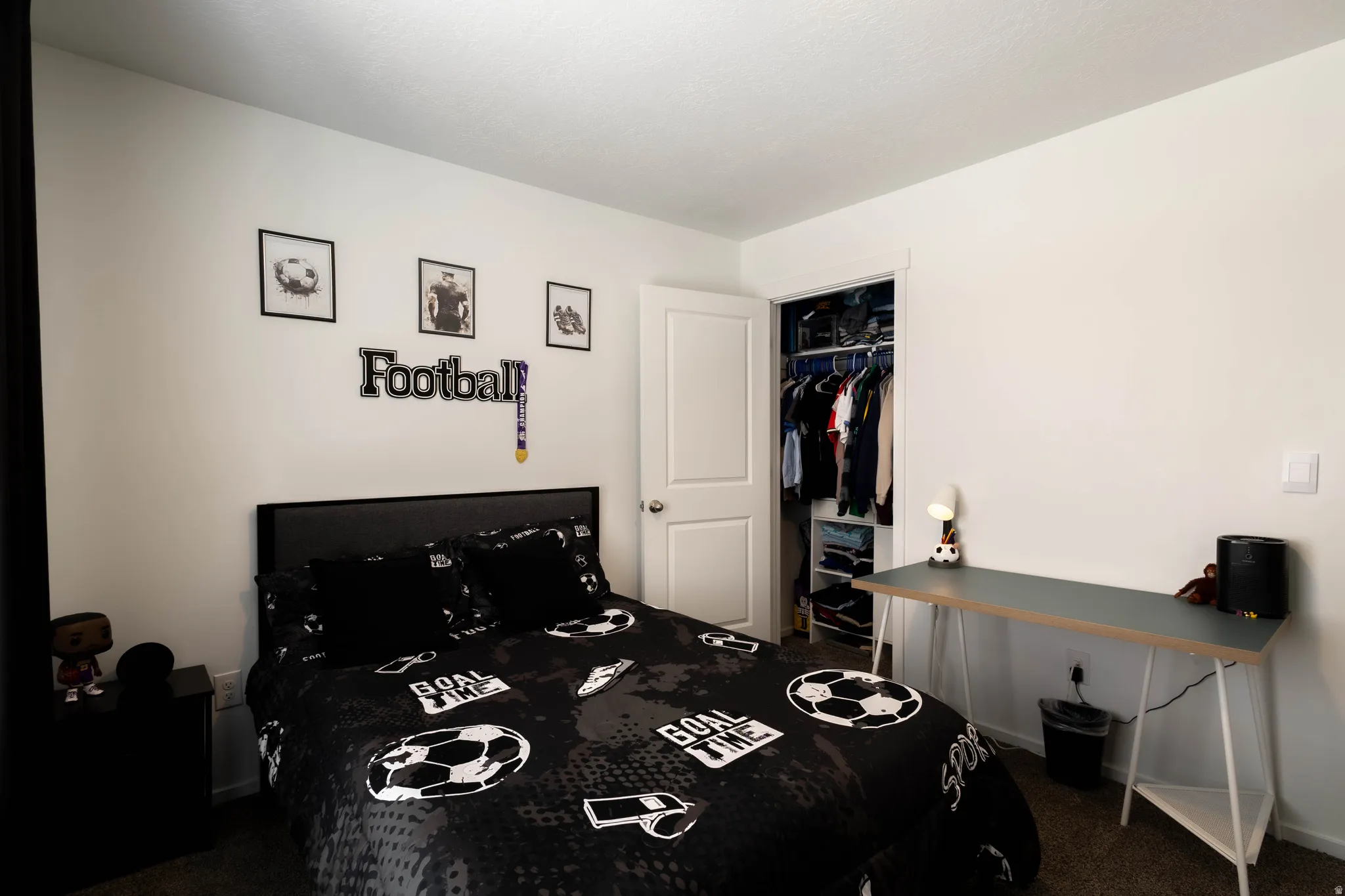 White walls and textured carpeting define this bedroom, featuring a built-in closet with shelving and hanging rods