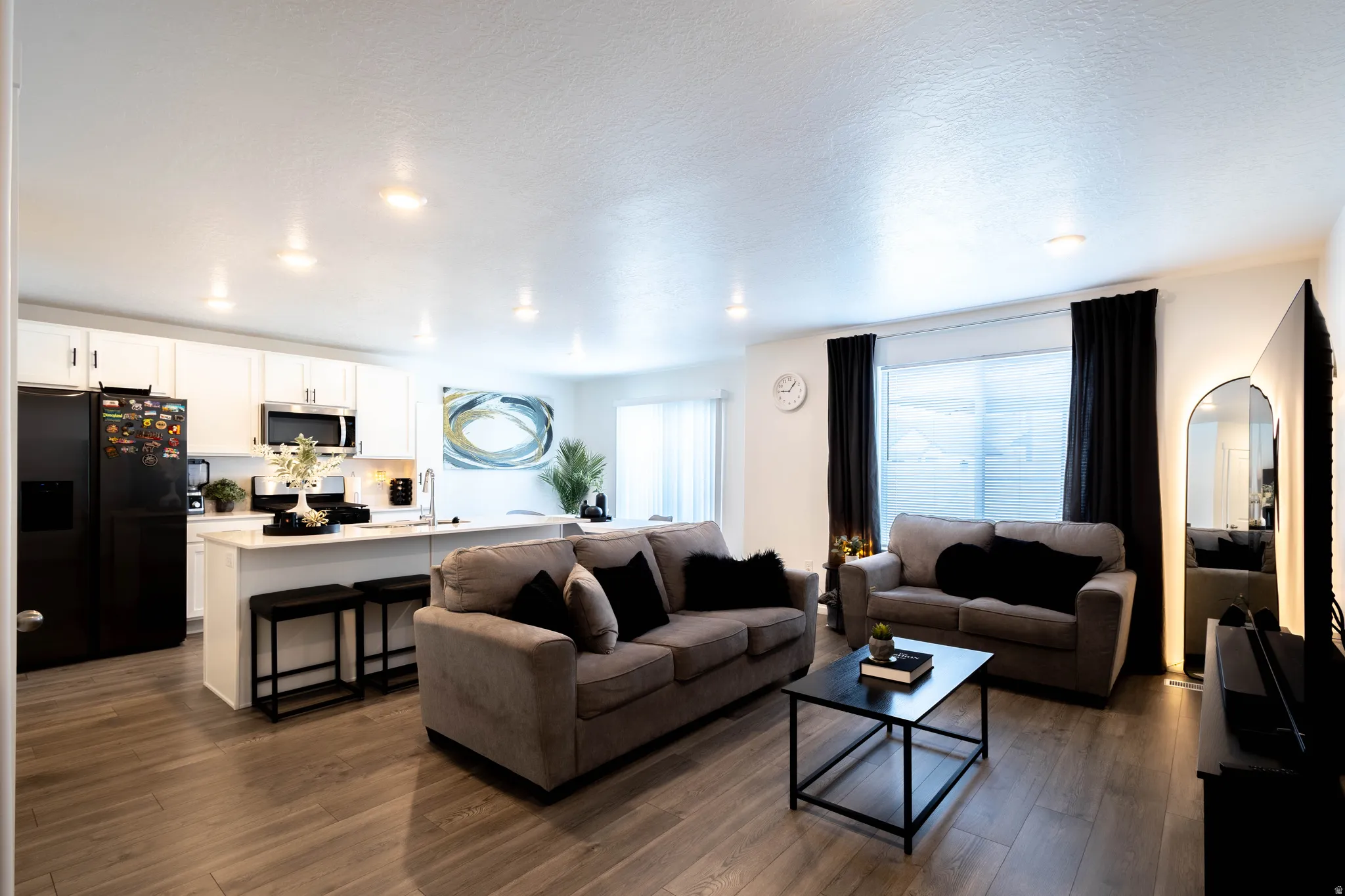Open-concept living area featuring wood-finish flooring throughout, recessed lighting, and a kitchen island with seating