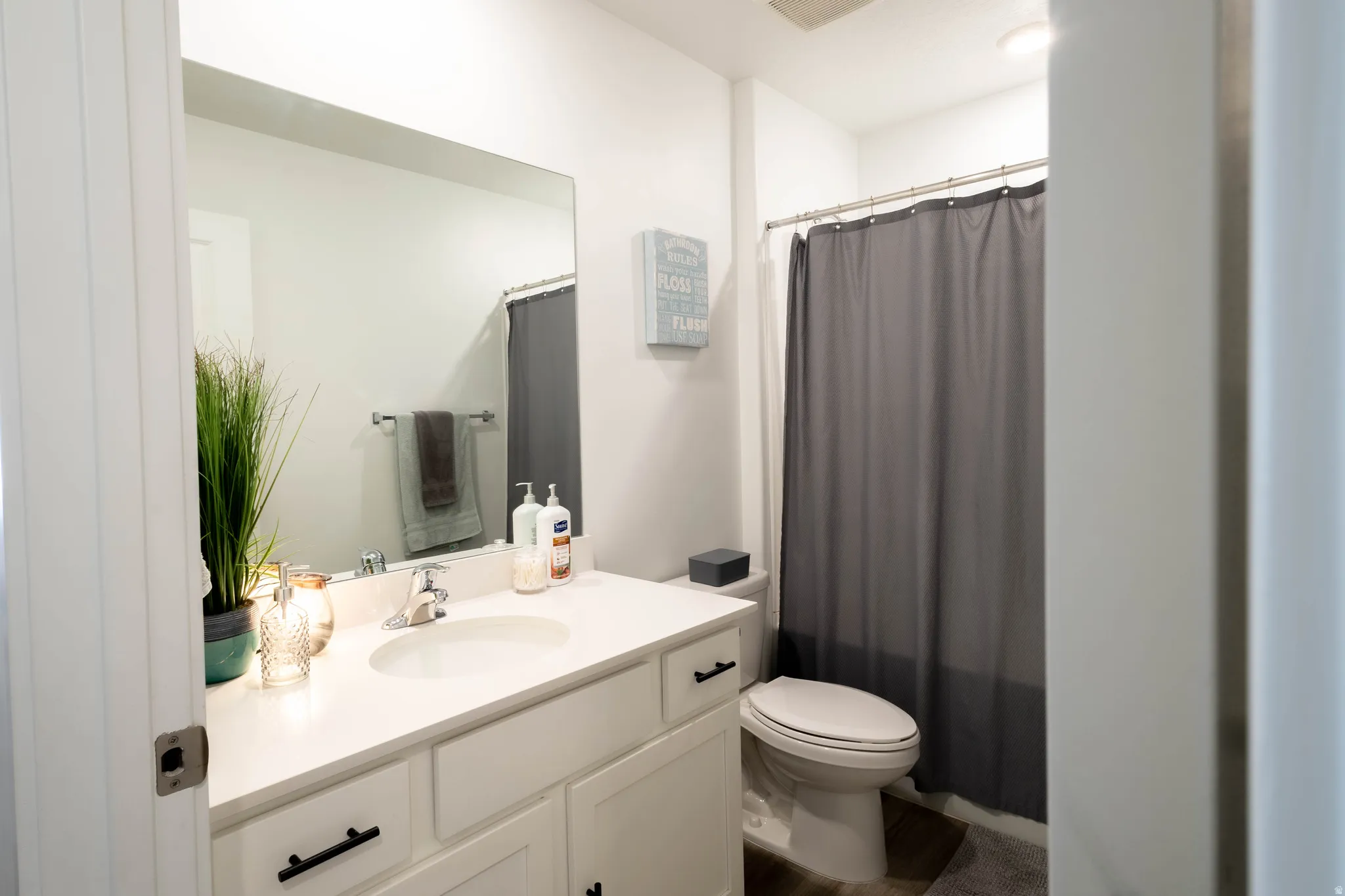 Bathroom featuring a white vanity with an integrated sink, polished chrome faucet, matte black cabinet hardware, and a framed mirror