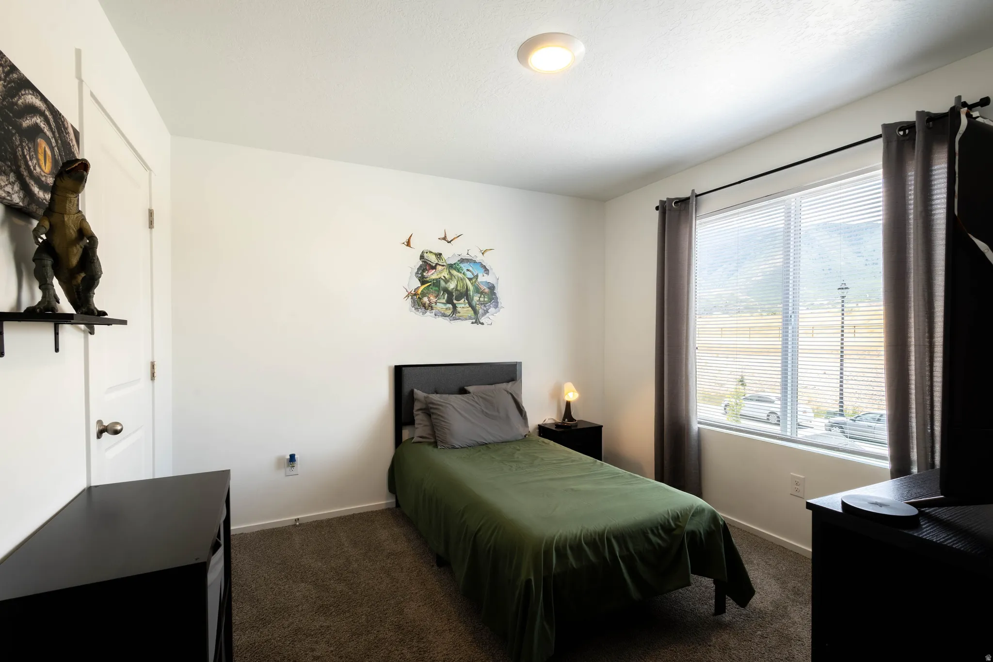 Bedroom featuring plush carpeting and a large window with horizontal blinds