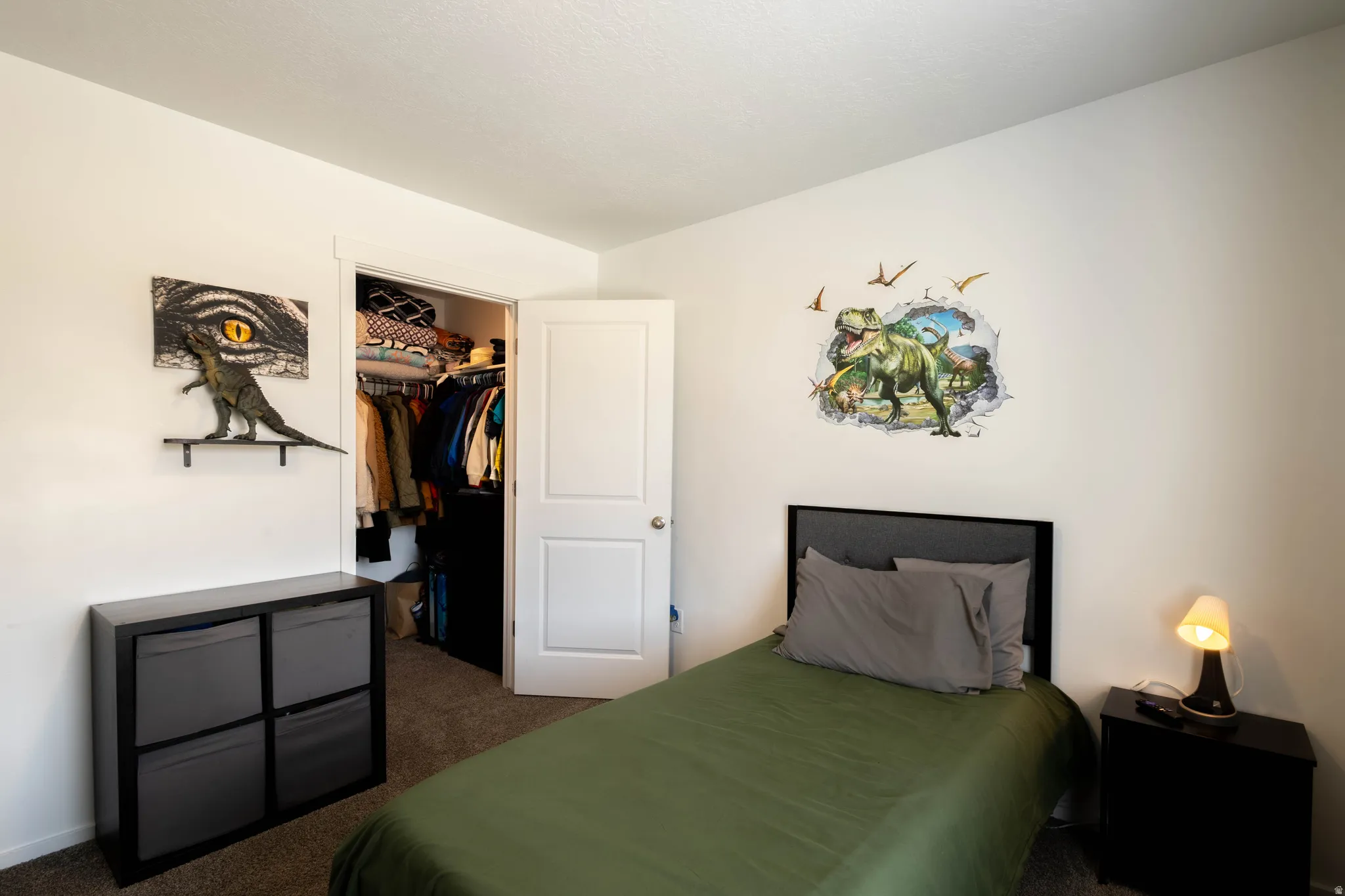 Bedroom featuring neutral paint, textured carpet flooring, a single-panel door, and a built-in closet with shelving and hanging storage