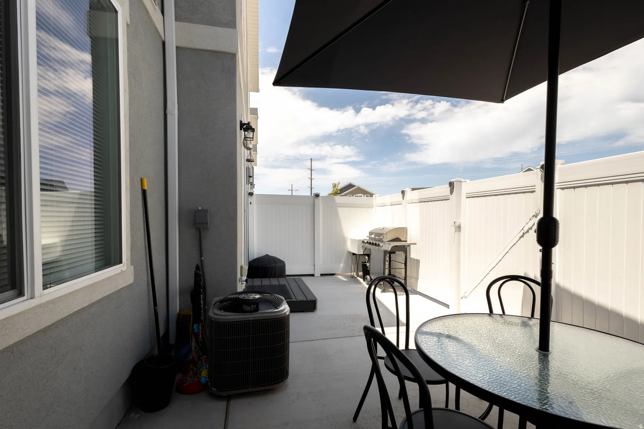 Private patio space featuring a concrete pad and white vinyl fencing