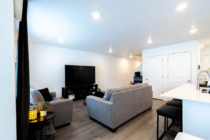 Open-concept living space featuring wood-finish flooring, recessed lighting, and a neutral color palette