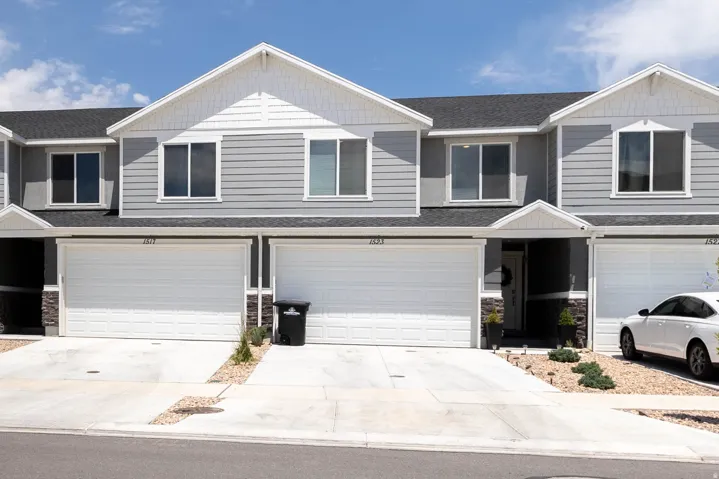 Contemporary townhome exterior featuring gray siding, white trim, and a dark shingle roof