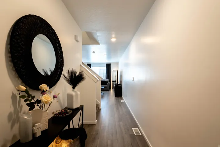 Entryway featuring wood-finish flooring, white walls, and a staircase with white risers and handrails