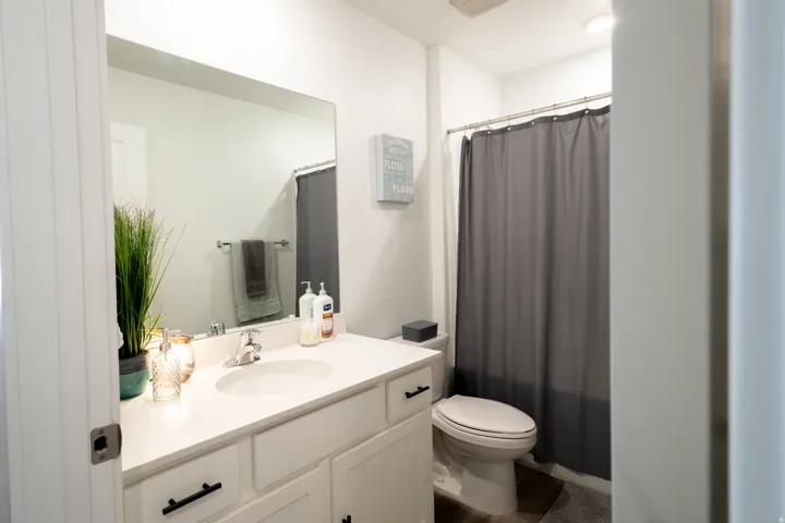 Bathroom featuring a white vanity with an integrated sink, polished chrome faucet, matte black cabinet hardware, and a framed mirror