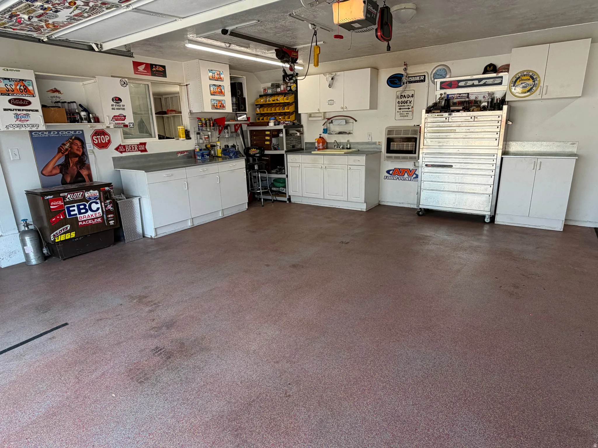 Spacious garage with textured flooring, extensive built-in cabinetry, and integrated work surfaces