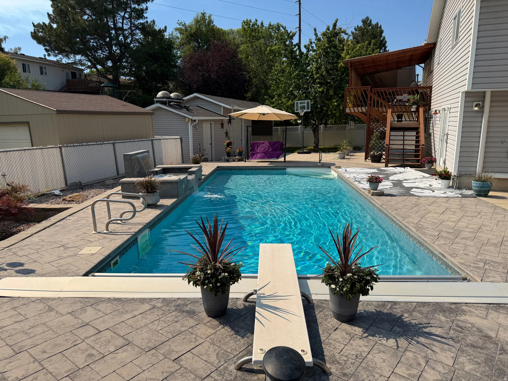 Rectangular swimming pool with a diving board, surrounded by stamped concrete decking