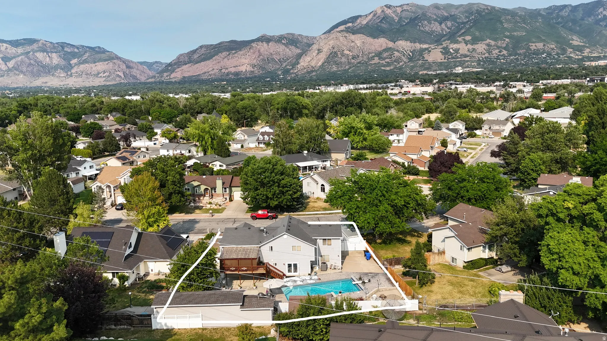Rear exterior featuring a swimming pool, wood deck, and mountain backdrop