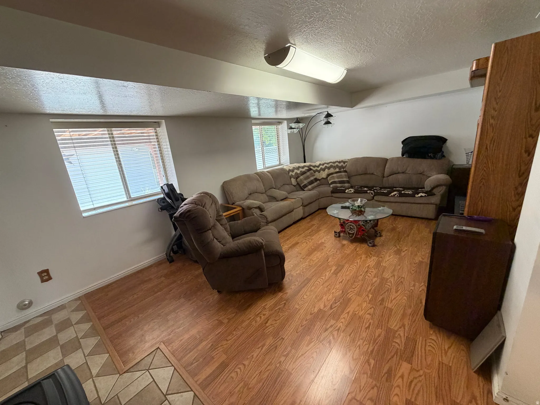 Spacious room featuring wood-finish flooring, white walls, and a dropped ceiling with integrated lighting