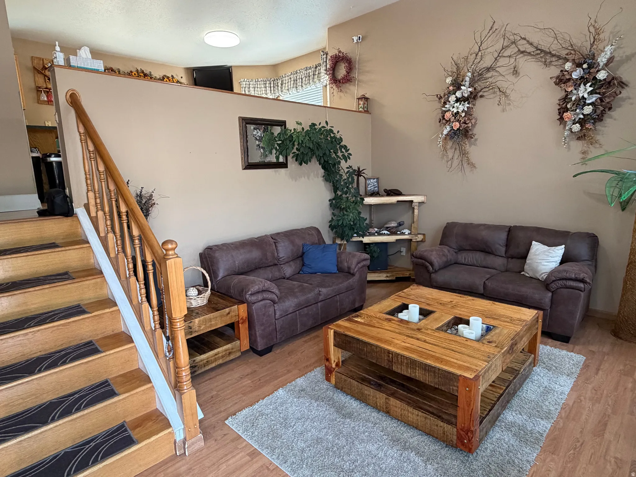 Warm living area featuring wood-finish flooring and a central staircase with a wood balustrade