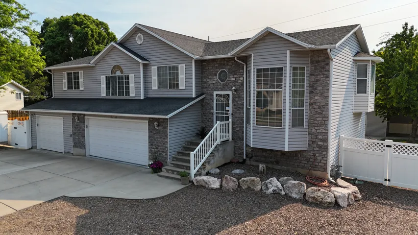 Two-story residence featuring light gray siding and stone veneer accents
