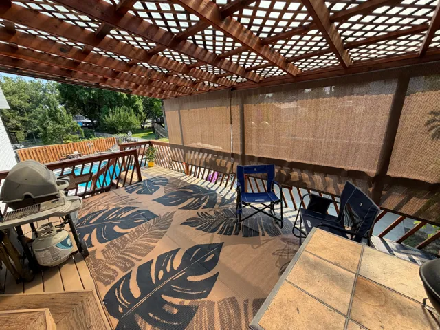 Expansive deck with wood-finish flooring, featuring a lattice-style pergola overhead