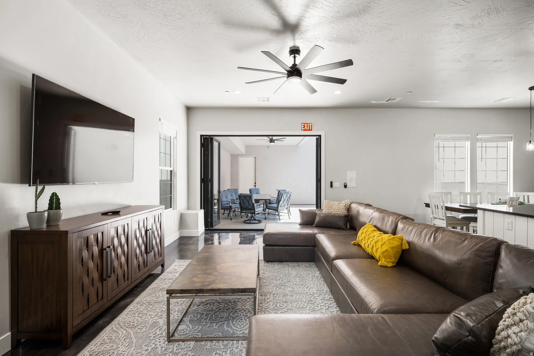 Spacious living area featuring a ceiling fan, dark wood-finish flooring, and a built-in media console