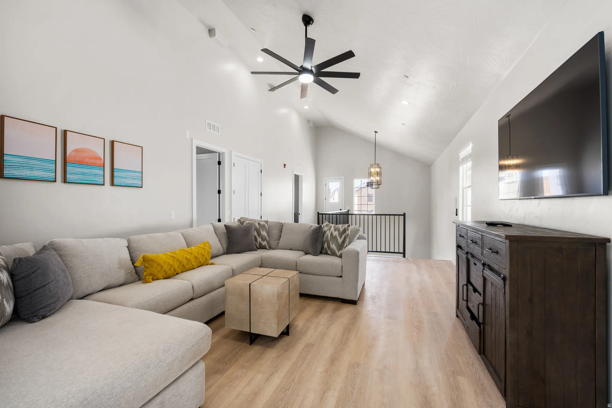 Spacious living area featuring light wood-finish flooring and a vaulted ceiling