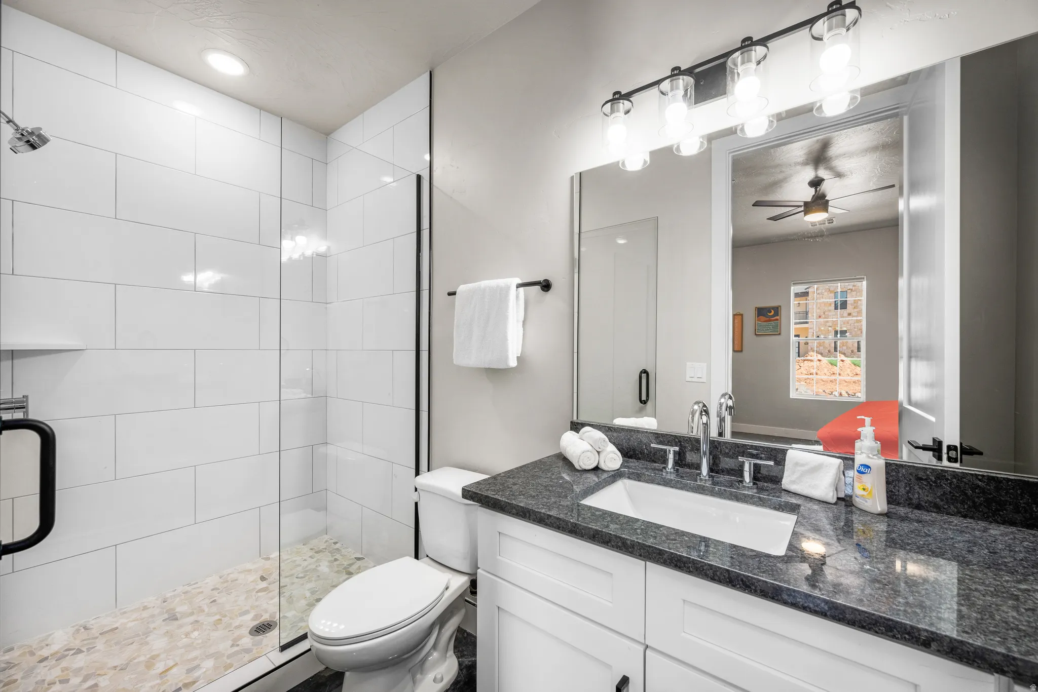 Bathroom featuring a glass-enclosed shower with subway tile surround and pebble tile flooring