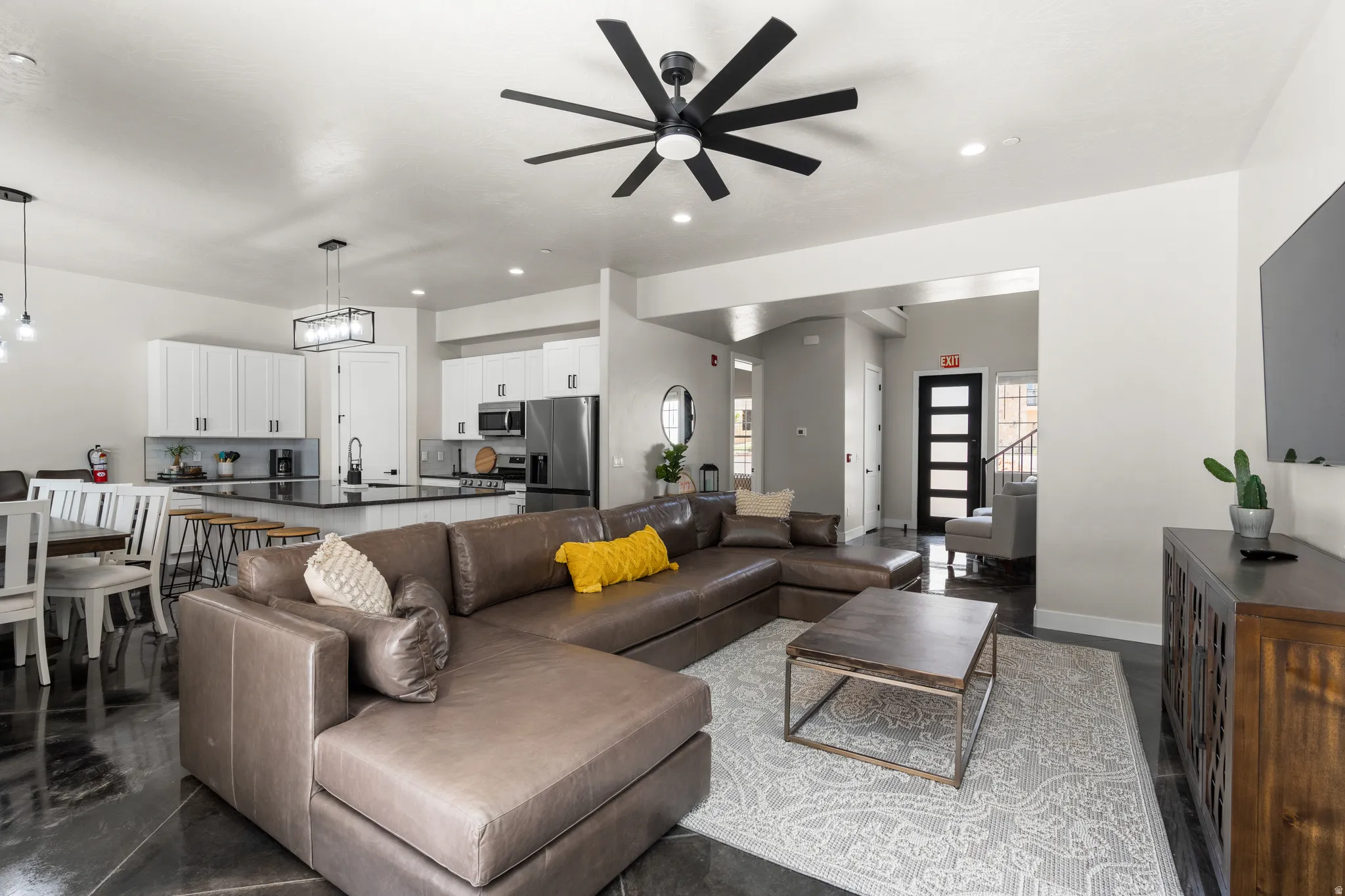 Open-concept living area featuring a modern black ceiling fan, recessed lighting, and dark-finish flooring