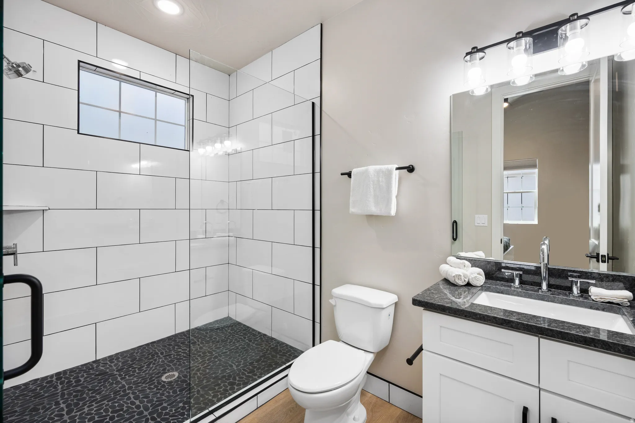 Bathroom featuring a glass-enclosed shower with white subway tile walls and a dark pebble-style floor