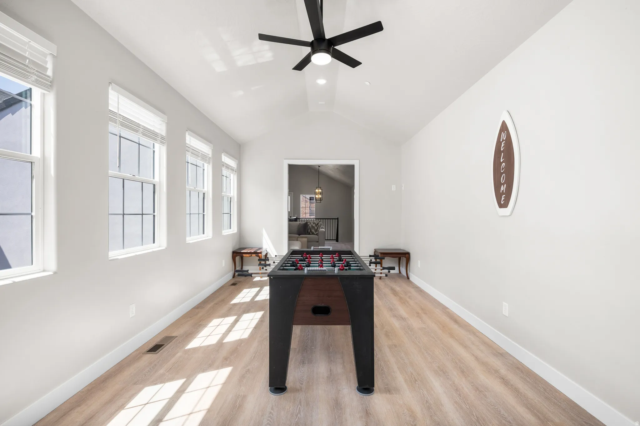 Spacious bonus room featuring vaulted ceilings, light wood-finish flooring, and a contemporary ceiling fan