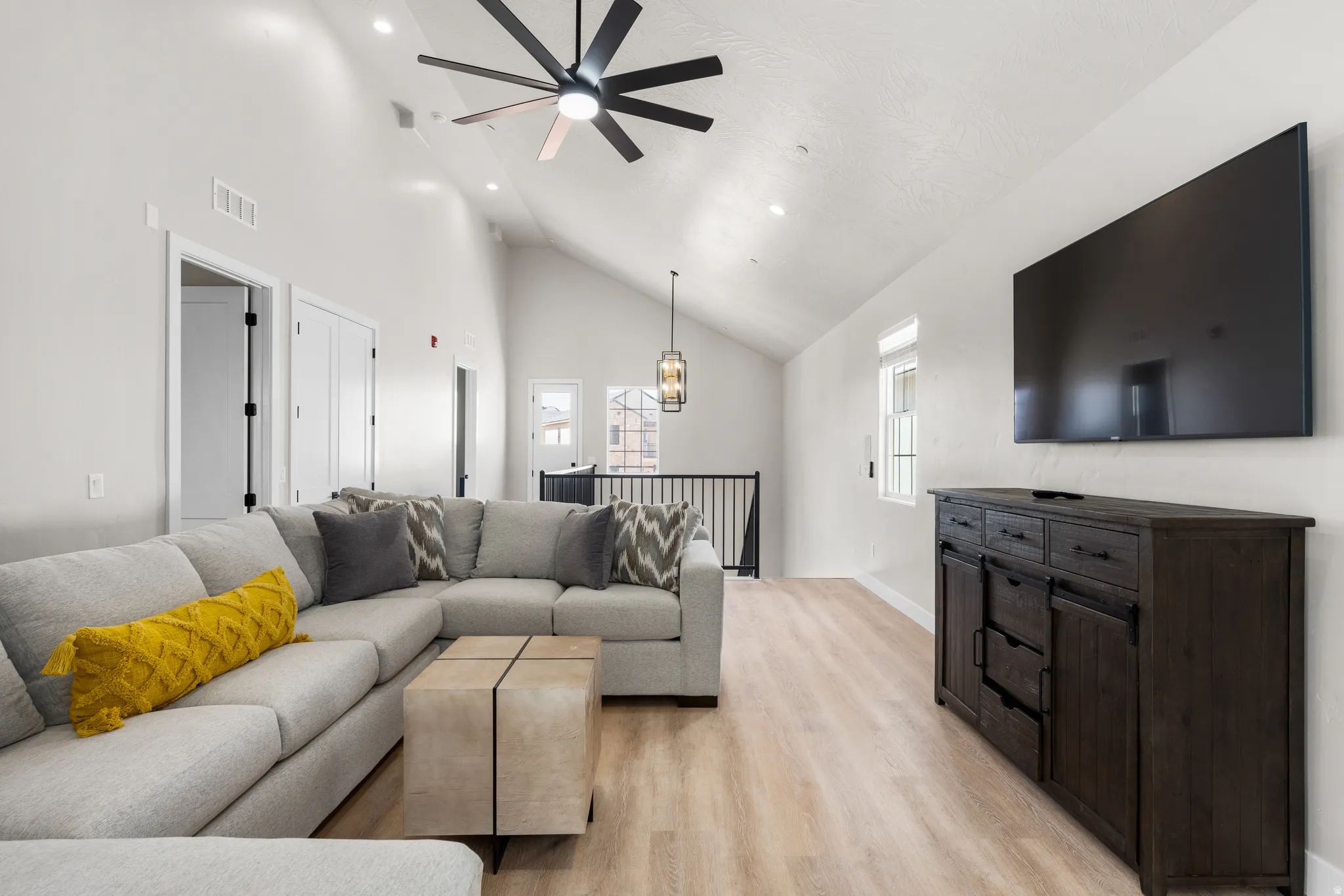 Vaulted ceiling with a contemporary ceiling fan, recessed lighting, wood-finish flooring, and a large window providing natural light
