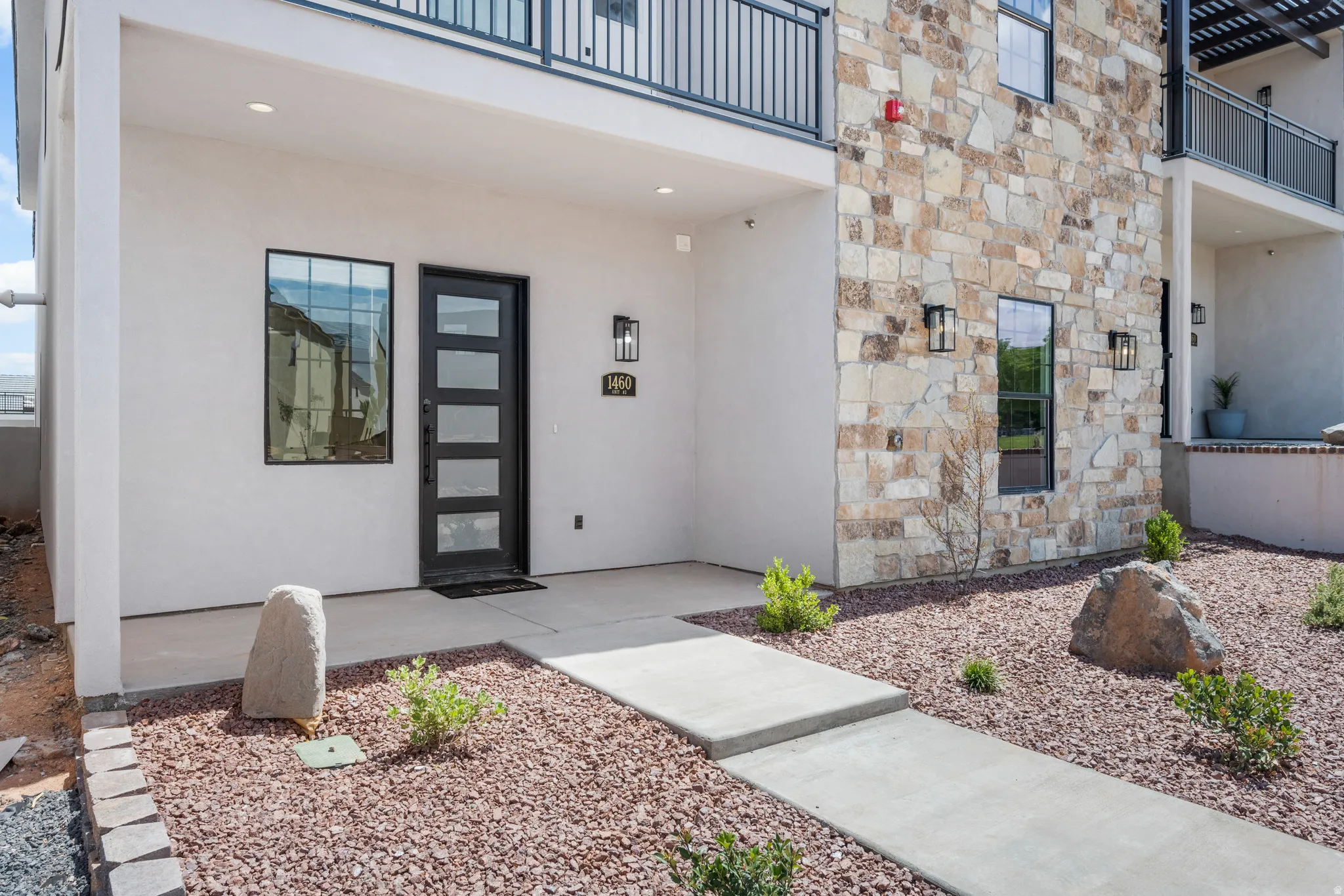 Contemporary entry featuring a black multi-pane door, flanking window, and matte black exterior lighting