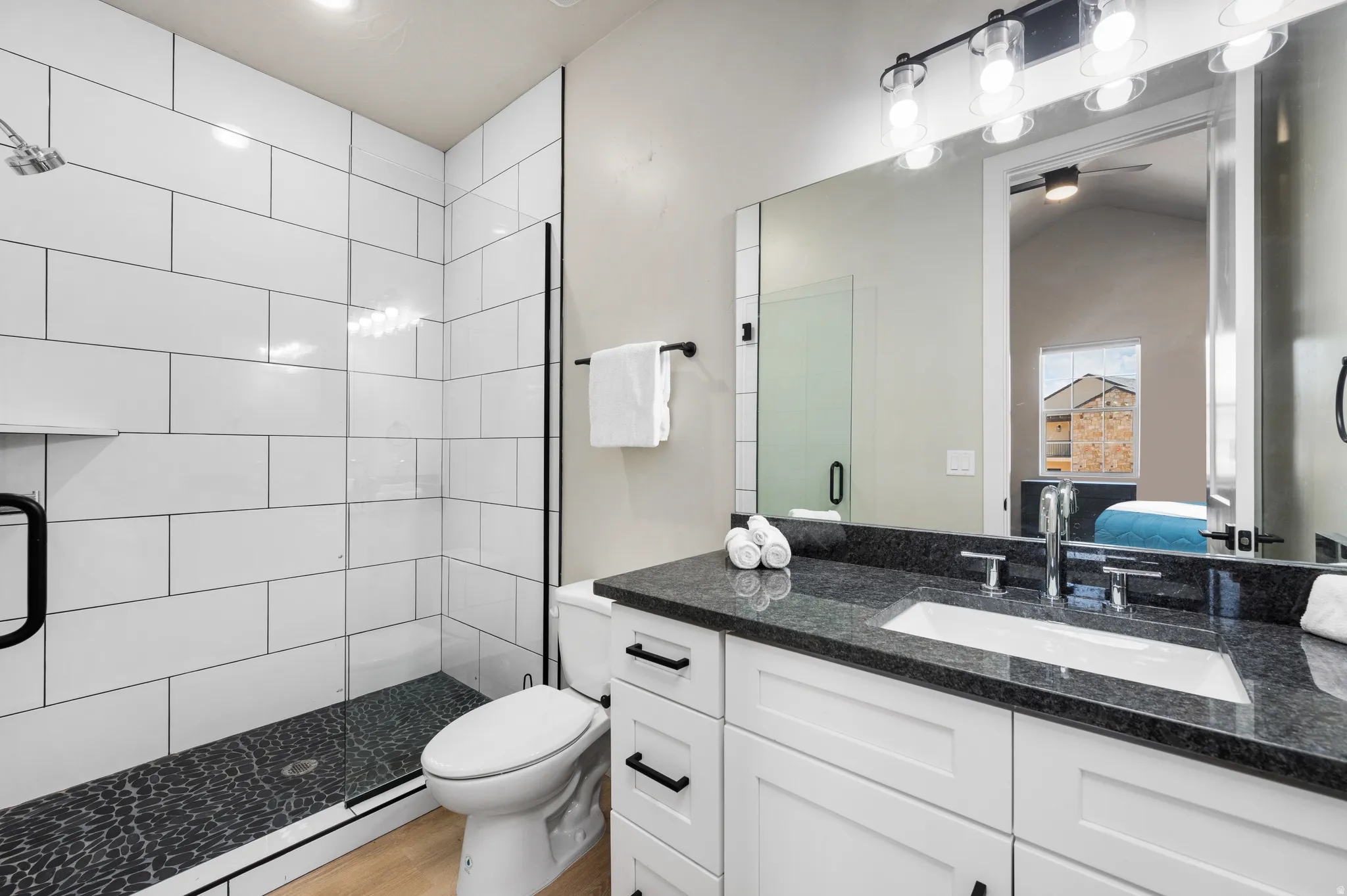 Modern bathroom featuring a vanity with a dark countertop, an undermount sink, and polished chrome fixtures