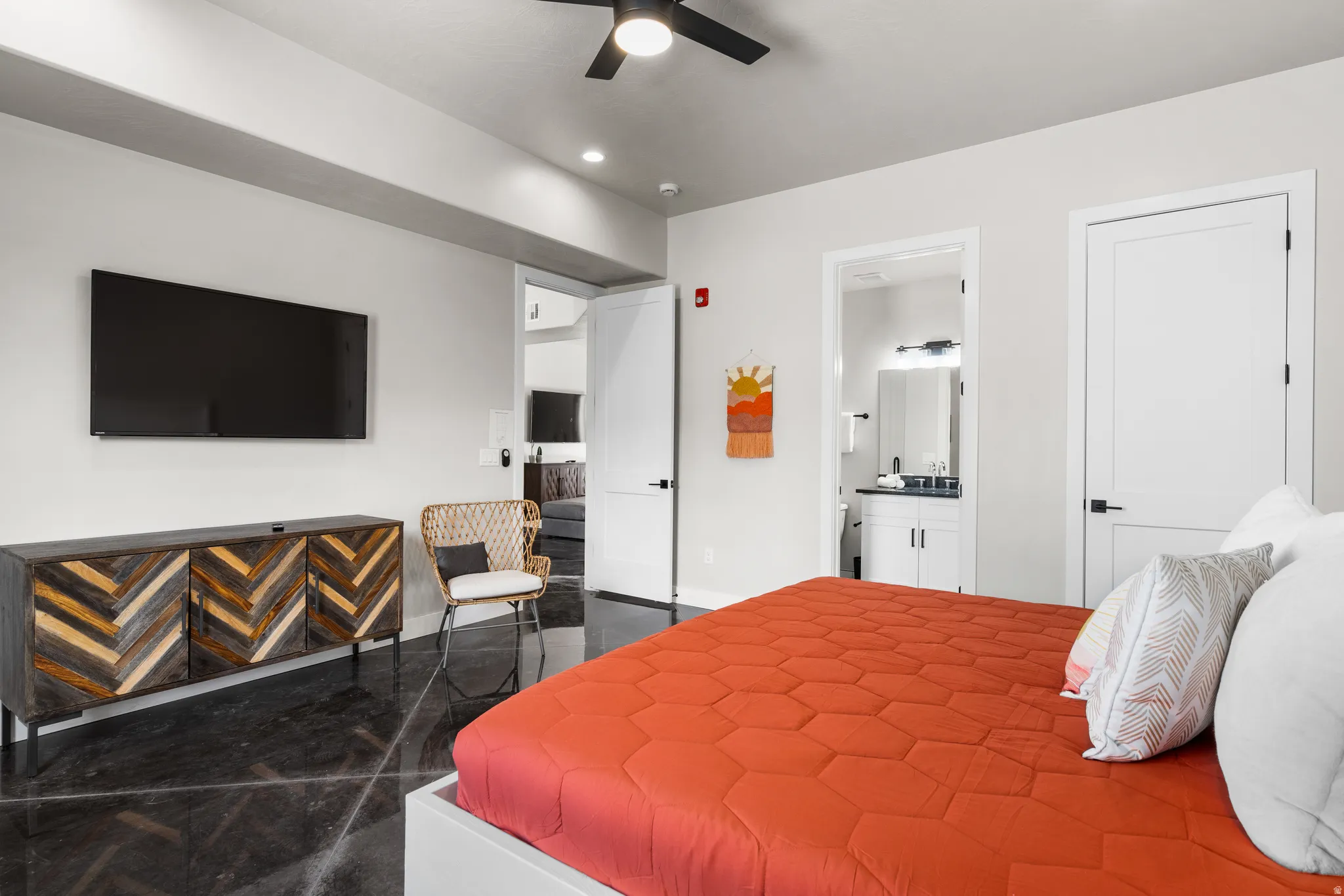 Spacious room featuring high ceilings, dark polished concrete flooring, a ceiling fan with integrated lighting, and a white interior door with matte black hardware