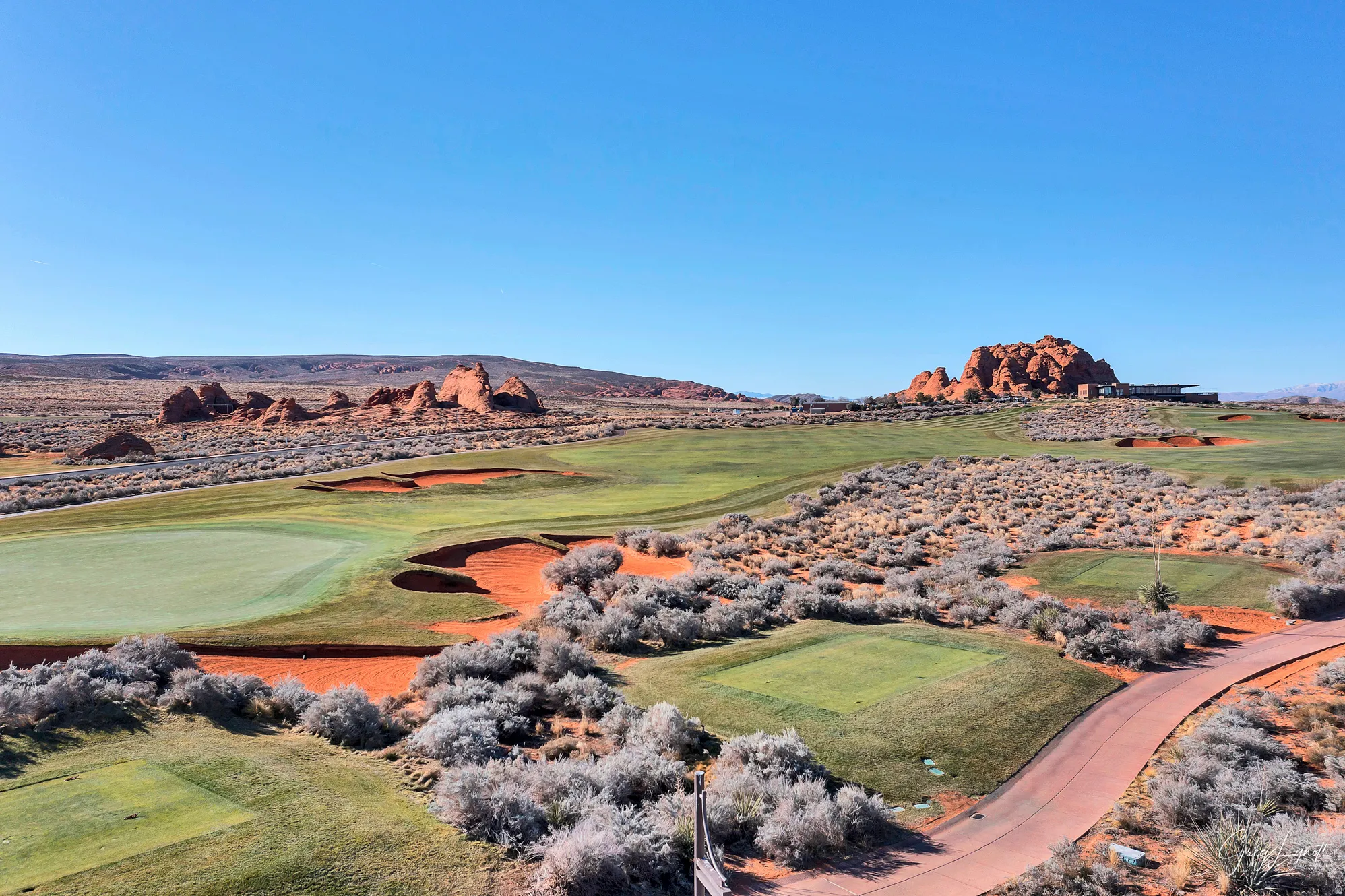 Expansive golf course featuring manicured greens and natural red rock landscaping