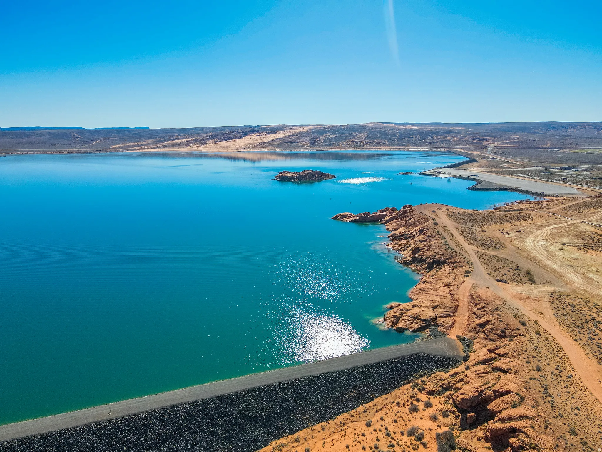Expansive body of water with a distinct blue-green hue, framed by arid, reddish-brown land