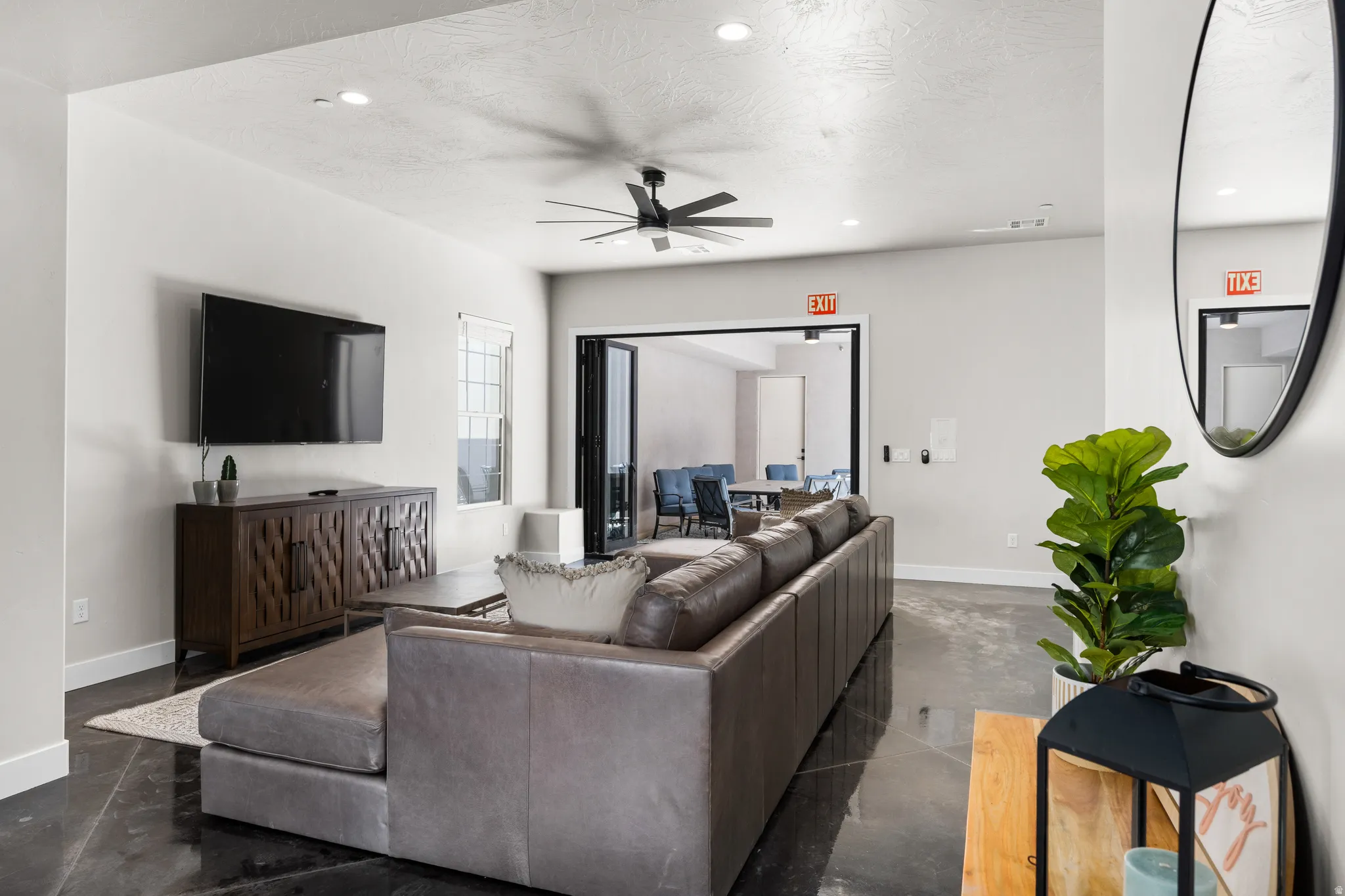 Spacious lounge area featuring a ceiling fan, recessed lighting, and dark-finish flooring