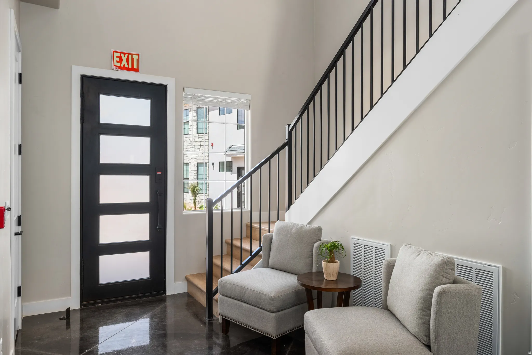 Entryway featuring a black door with frosted glass panels, dark polished flooring, and a modern staircase with black wrought iron spindles and wood treads