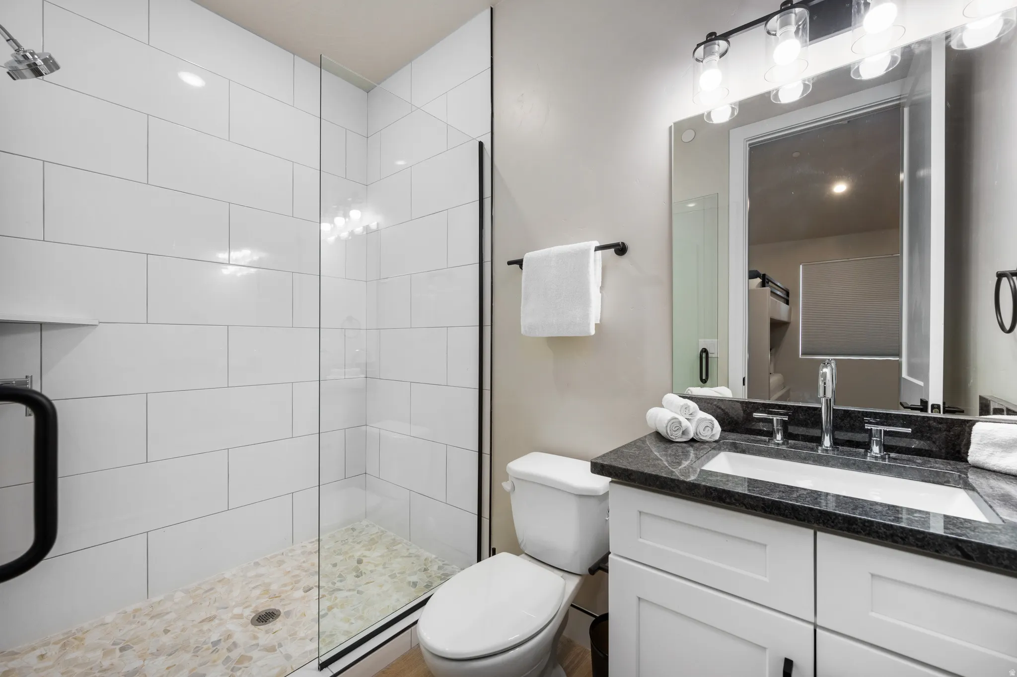 Bathroom featuring a glass-enclosed shower with white subway tile, pebble flooring, and a built-in shower niche