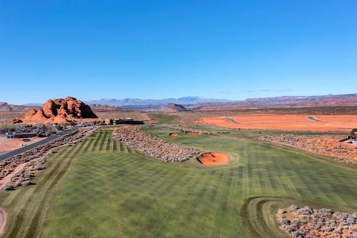 Expansive golf course landscape featuring meticulously manicured greens, natural desert vegetation, and striking red rock formations
