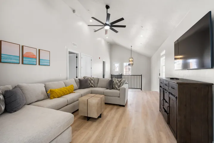 Spacious living area featuring light wood-finish flooring and a vaulted ceiling