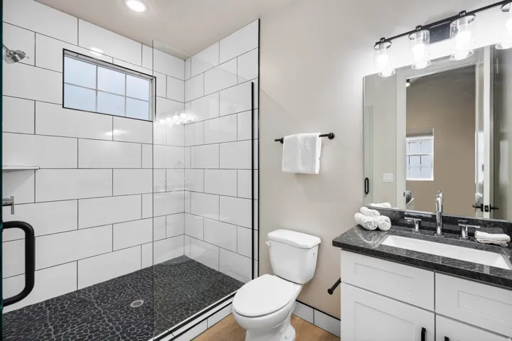 Bathroom featuring a glass-enclosed shower with white subway tile walls and a dark pebble-style floor