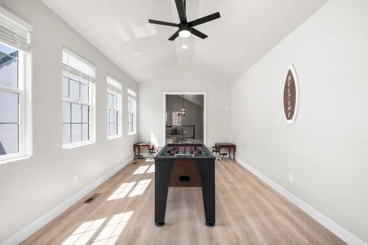 Spacious bonus room featuring vaulted ceilings, light wood-finish flooring, and a contemporary ceiling fan