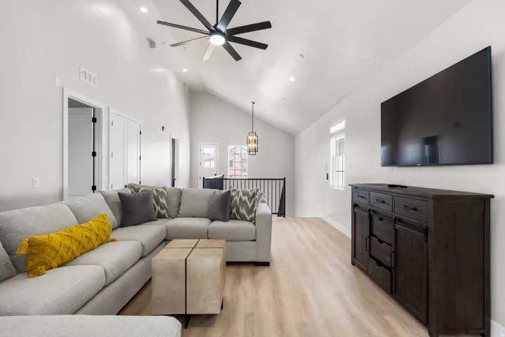 Vaulted ceiling with a contemporary ceiling fan, recessed lighting, wood-finish flooring, and a large window providing natural light